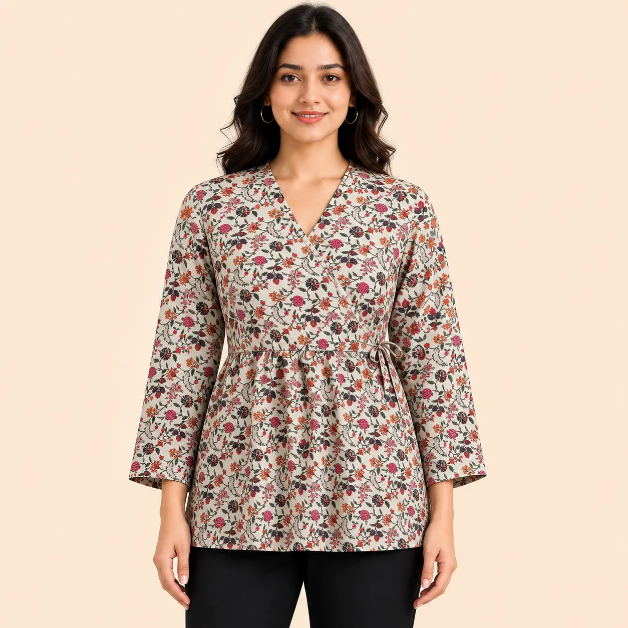 Women's floral print wrap style hip length kurti in beige featuring a V-neckline, full sleeves, adjustable waist tie, and multicolor floral pattern. Styled with black pants, this lightweight casual kurti from Voniva Fashion is ideal for everyday wear, office wear, and festive casual occasions. High-quality studio product image with clear fabric texture and stitching details.