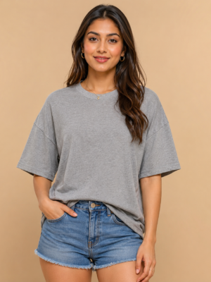 Woman wearing a grey melange oversized t-shirt with drop-shoulder half sleeves, round neck, and relaxed boxy fit, styled with denim shorts - front view